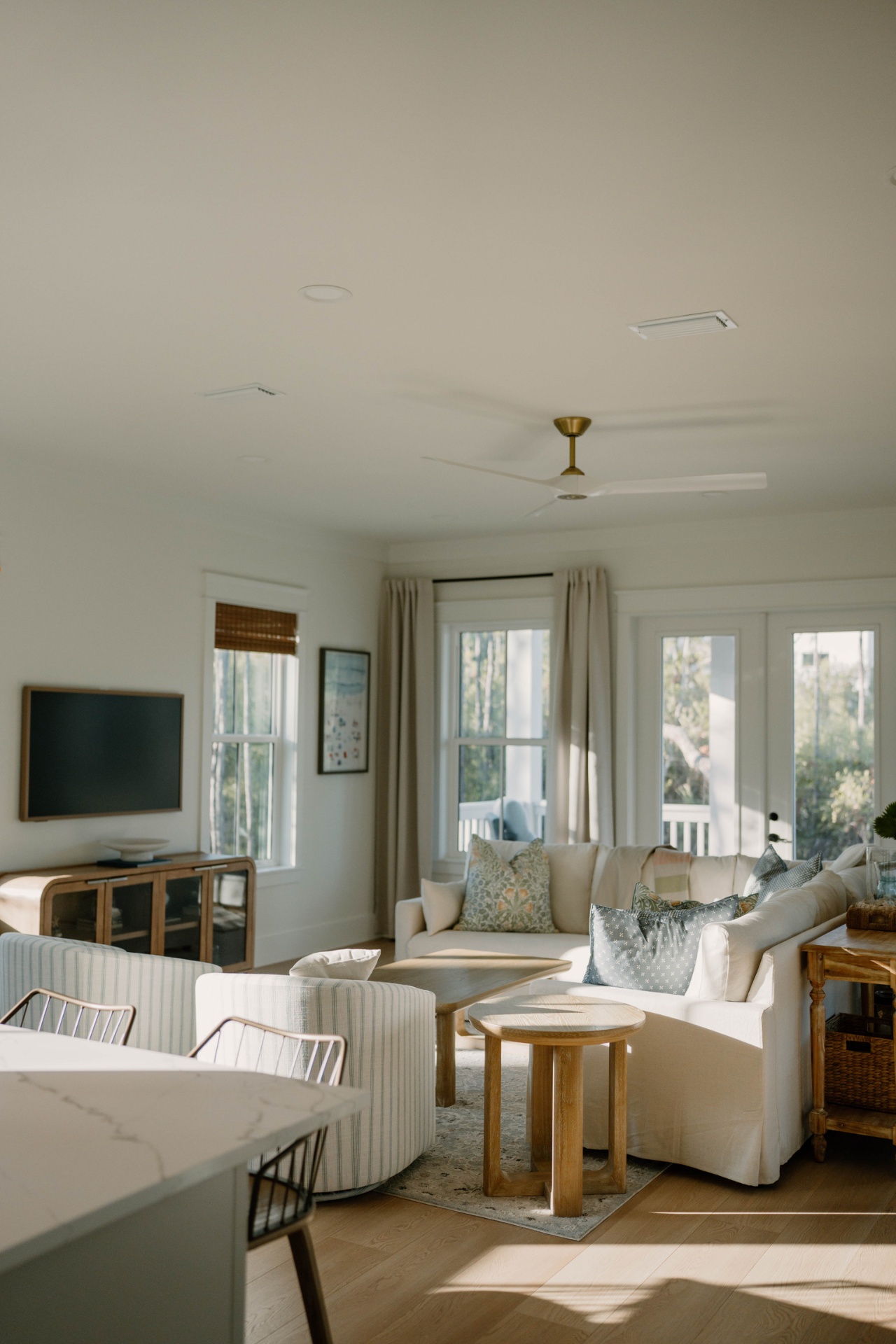 Bright coastal living room with ceiling fan and water views